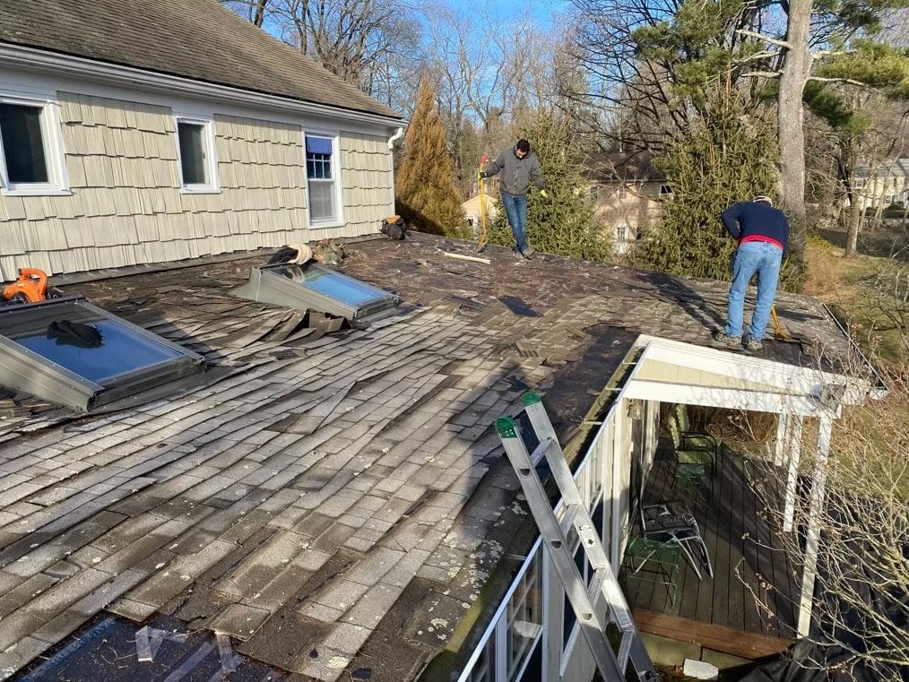 RC Carpentry & Roofing crew stripping damaged shingles during roof repair on a Fairfield County home with skylights